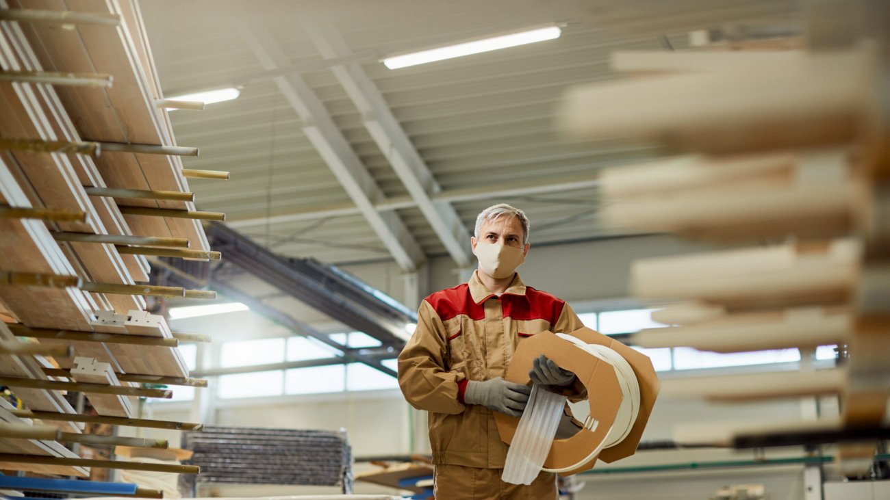 Low angle view of manual worker carrying protective foam while working at carpentry warehouse.